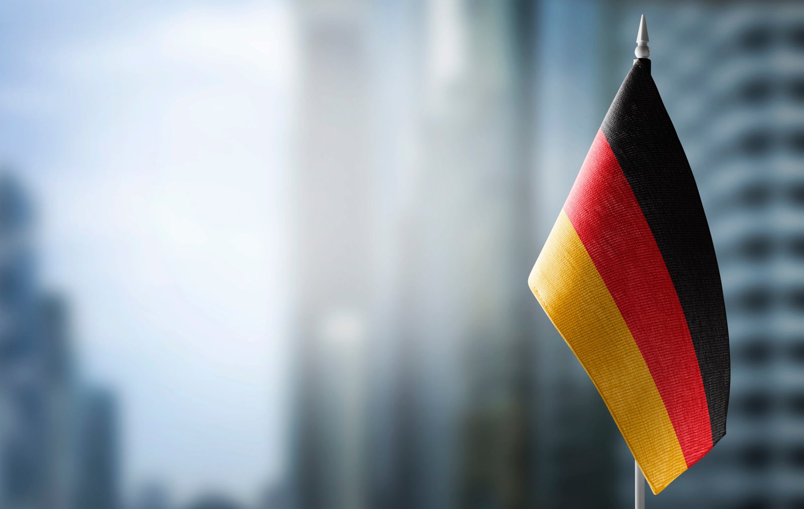 German flag with blurred city in the background, symbolizing European policy and governance.